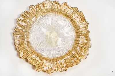Glass charger with a gold-tinted ruffled rim and clear textured centre, photographed from above