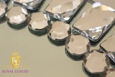 Close-up of faceted round and rectangular clear jewels set along the rim of a mirrored charger