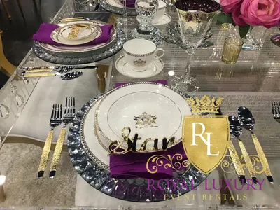Mirrored charger with jeweled rim holding white gold-trimmed china and a purple napkin at a styled place setting