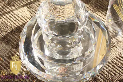 Top-down close-up of the faceted crystal base of a candelabra on a patterned brown carpet in sunlight