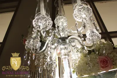 Low angle view of candelabra arms with hanging crystal drops and tulip shades, beside white and pink flowers