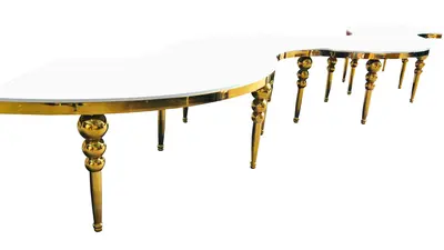 Gold bubble-legged tables with glossy white tops joined in a long serpentine line, seen at a low angle