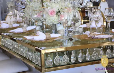 Close-up of the gold-framed glass table edge with hanging crystal drops, gold charger plates and champagne flutes