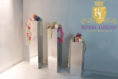 Three silver mirrored flower stands of different heights topped with pink and white blooms and candles, styled in a pale room