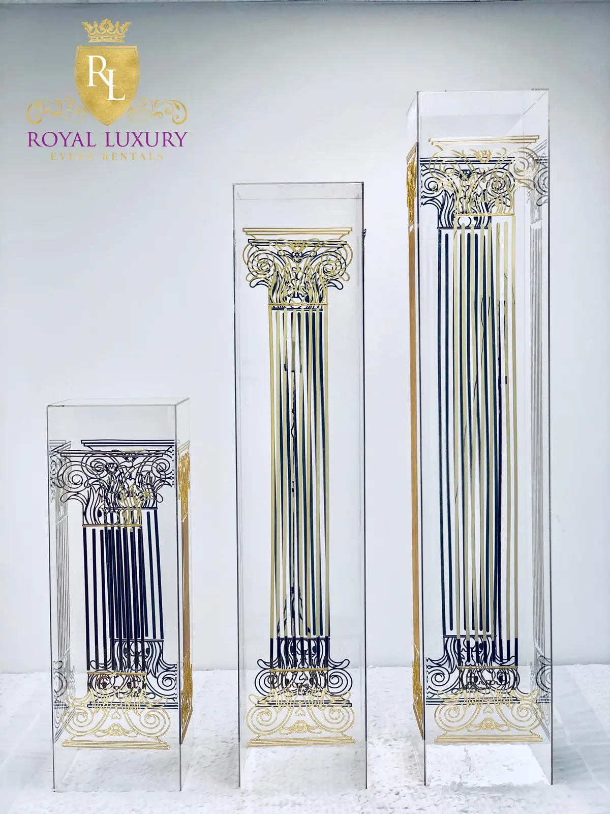 Three clear acrylic flower stands of different heights with gold and black engraved column designs