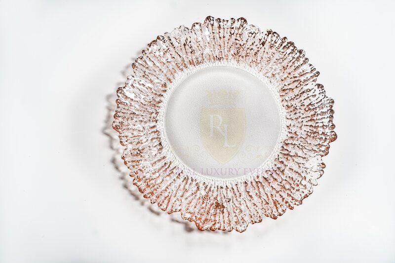 Round glass charger plate with a textured, ruffled rim edged in rose gold, seen from above