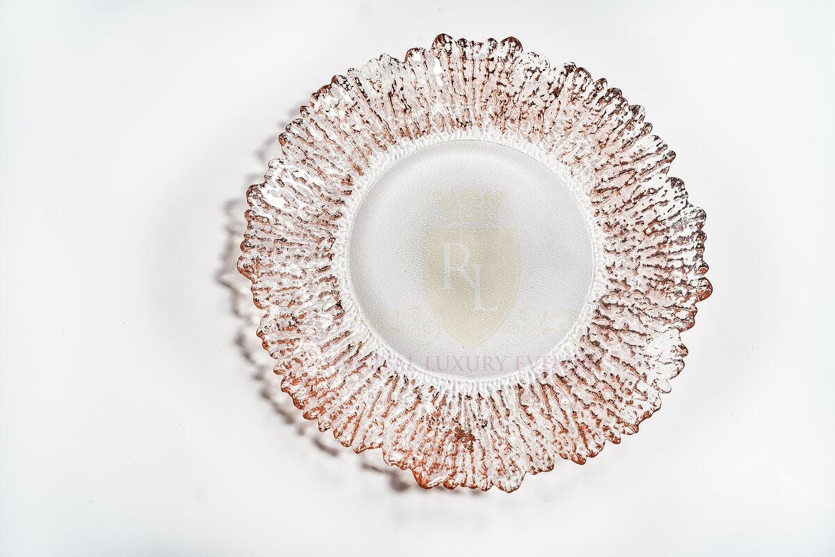 Round glass charger plate with a textured, ruffled rim edged in rose gold, seen from above