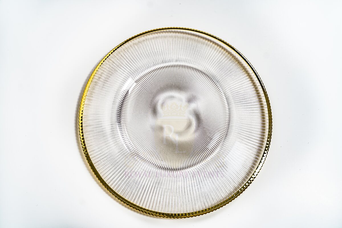 Clear ribbed glass charger plate with a gold rim, photographed from above