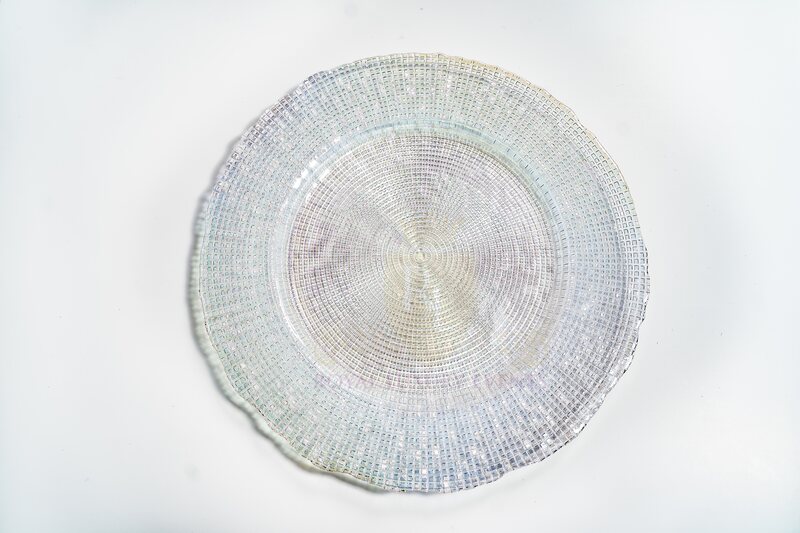 Clear iridescent glass charger plate seen from above, with a fine woven grid texture and softly scalloped rim