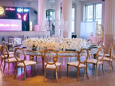Round gold-framed table with crystal-edged glass top, dressed with white floral centrepiece and crystal candelabras