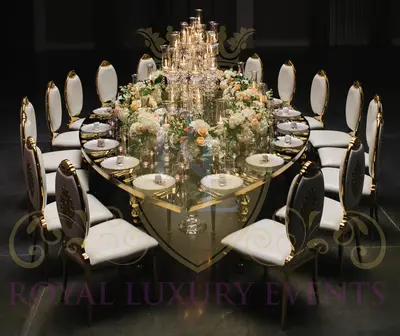 Gold teardrop dining table with mirror top, set with white florals, candles and ivory chairs, seen from above