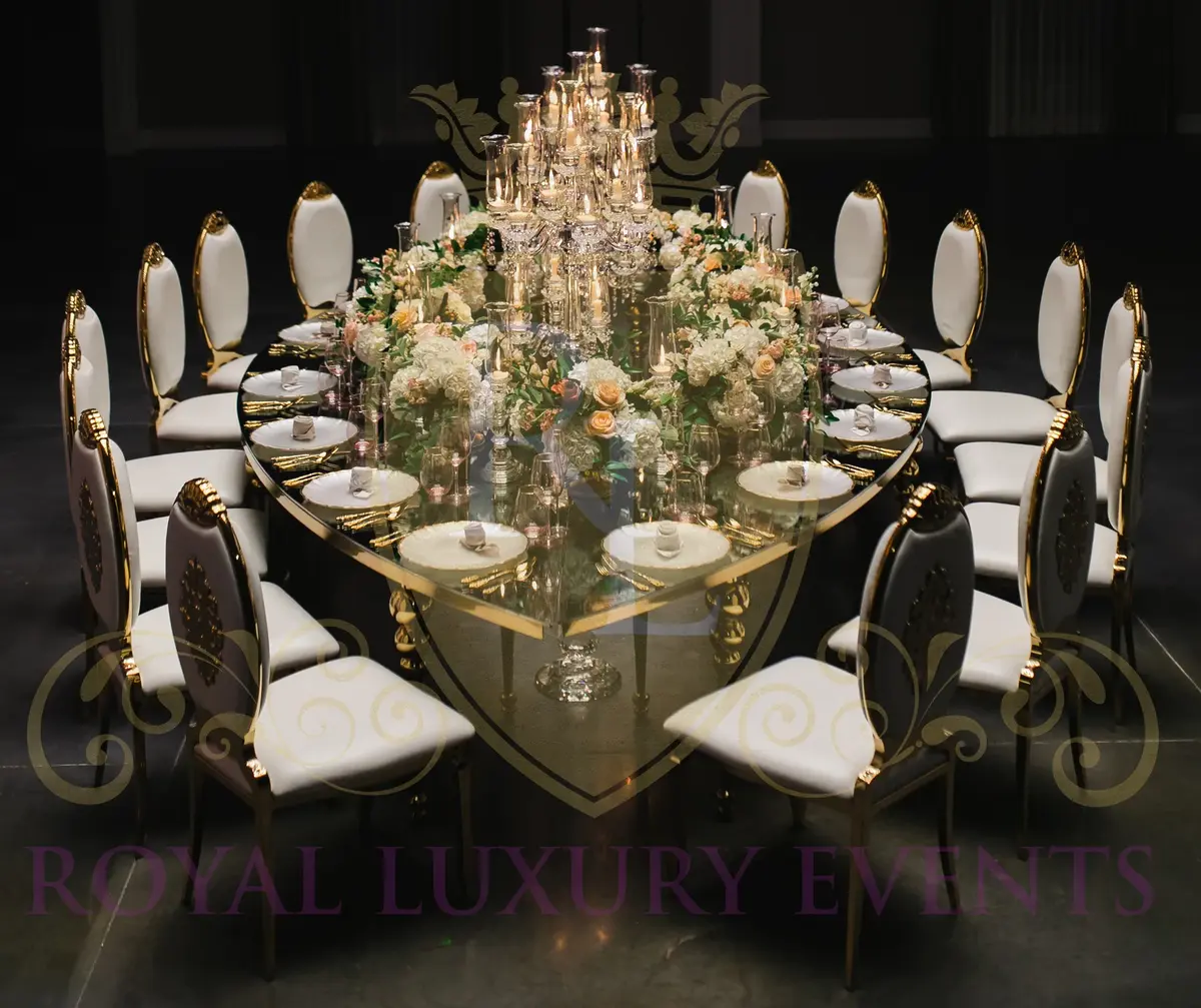Mirror-topped teardrop table seen from above, set with peach and white florals, candles and white chairs with gold trim