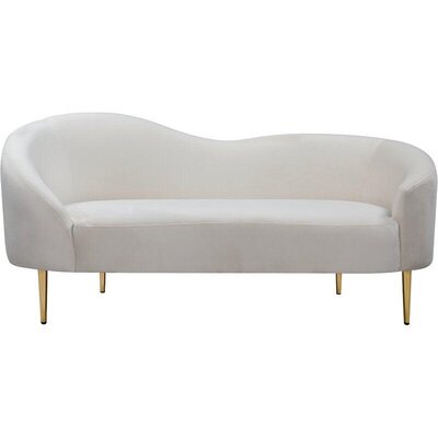 Curved loveseat in cream suede with a low wavy back and slim gold legs, front view