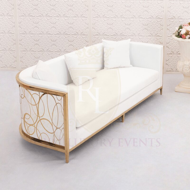 White lounge sofa with curved gold frame and looping gold scroll panel on the arm, shown with three white pillows