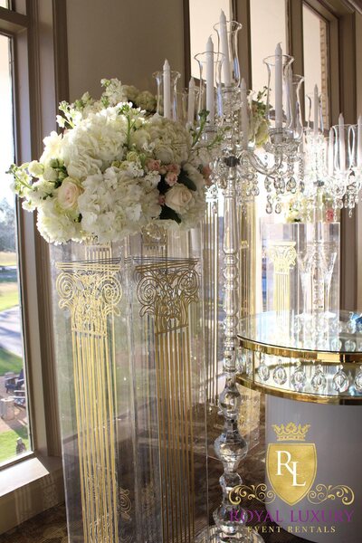 Crystal floor candelabra with white tapers, styled beside tall white floral arrangements and gold-etched clear pillars