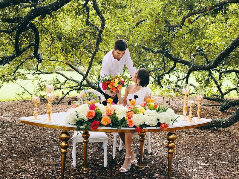 outdoor wedding reception - white chairs - pink napkins, charger plates, gold tableware, floral table runner, wedding cake, pink, yellow, orange, bouquet, houstonian, royal luxury events