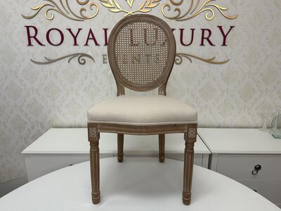 Front view of wooden Louis chair with oval mesh back, cream cushioned seat and carved leg details, showroom setting