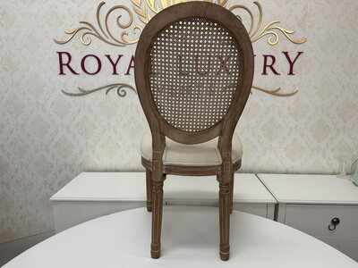 Rear view of wooden Louis chair showing the oval frame, woven mesh back panel and fluted legs, showroom setting