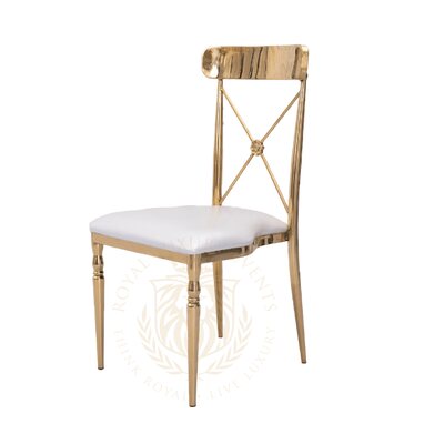 Cross-back chair with polished gold metal frame and white seat cushion, shown at a three-quarter angle