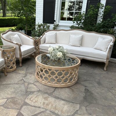 Lounge set with off-white upholstered chairs and sofa on a flagstone patio, white roses on the round coffee table