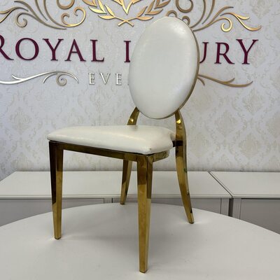 Side view of a white oval-back chair with polished gold legs on a white table in a showroom