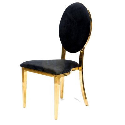 Black velvet dining chair with oval back and polished gold frame, shown from a three-quarter side angle