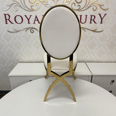Rear view of gold oval-back chair showing the crossed gold legs behind the white velvet backrest, on a white table
