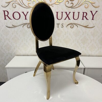 Gold chair with oval black velvet back and seat, curved polished legs, shown in the showroom