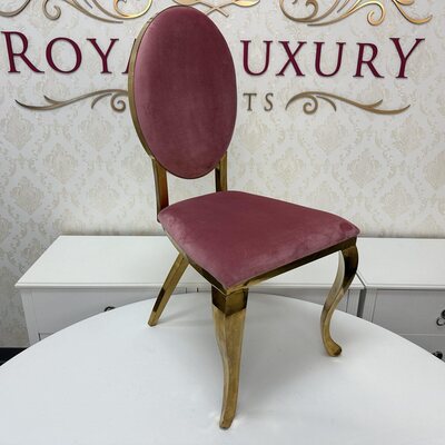 Gold chair with oval pink velvet back and seat, curved cabriole legs, shown on a white table in a showroom