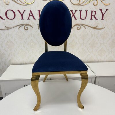 Front view of gold chair with navy velvet cushion, set against a damask wall and white table