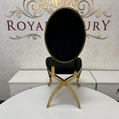 Rear view of gold chair showing crossed gold legs and oval black velvet back, set on a white table