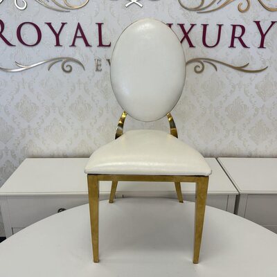 White oval-back chair with gold legs, seen from the front on a round white table in a showroom